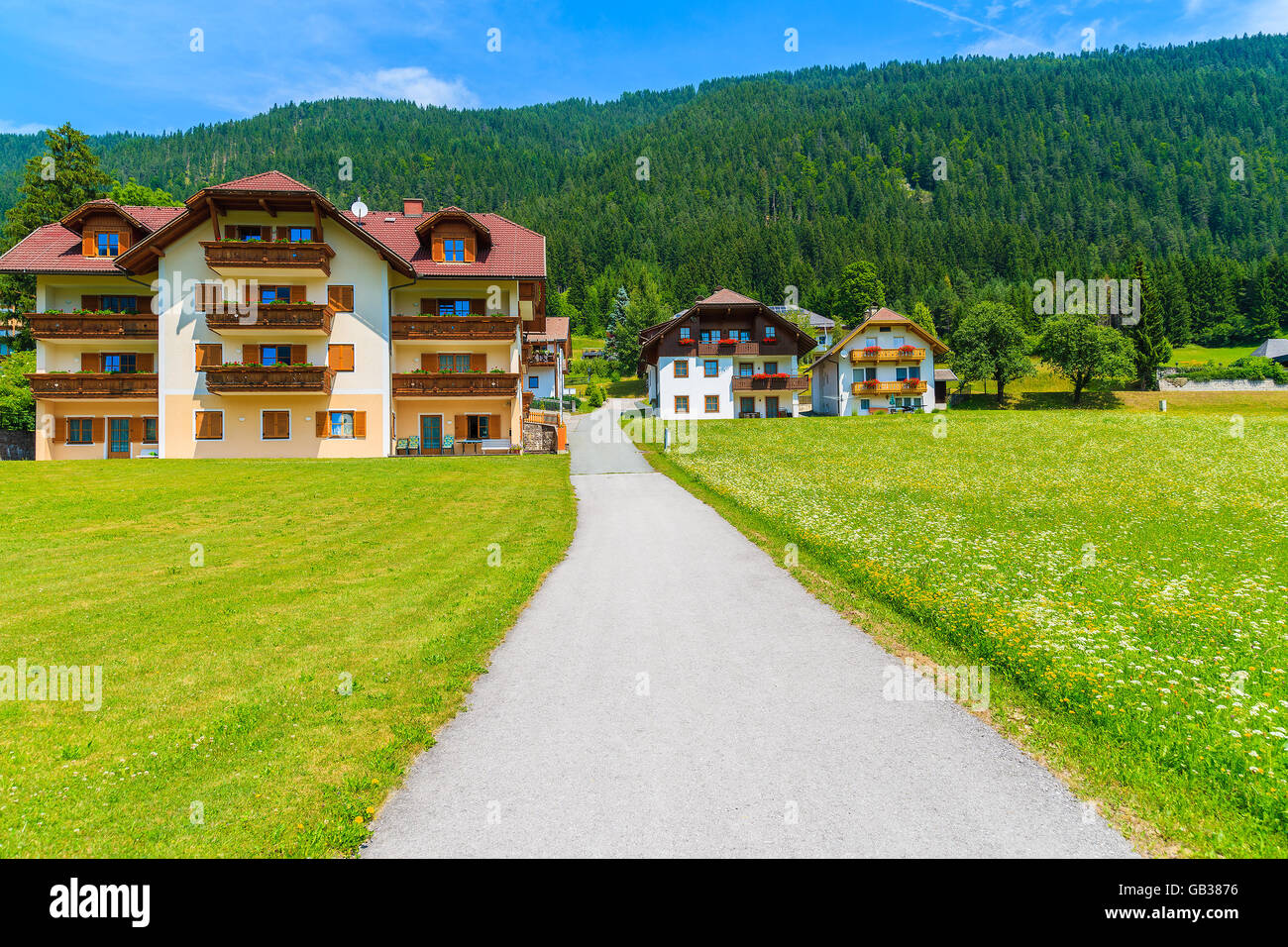 Road in alpine village with traditional houses near Weissensee lake in summer landscape of Carinthia land, Austria Stock Photo