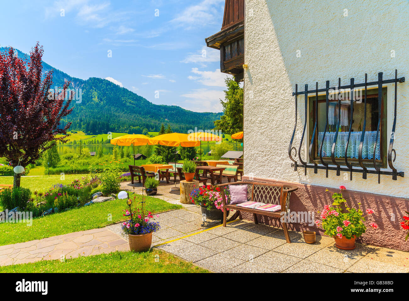 WEISSENSEE LAKE, AUSTRIA - JUL 6, 2015: Alpine house with restaurant garden on shore of Weissensee lake, Carinthia land, Austria Stock Photo