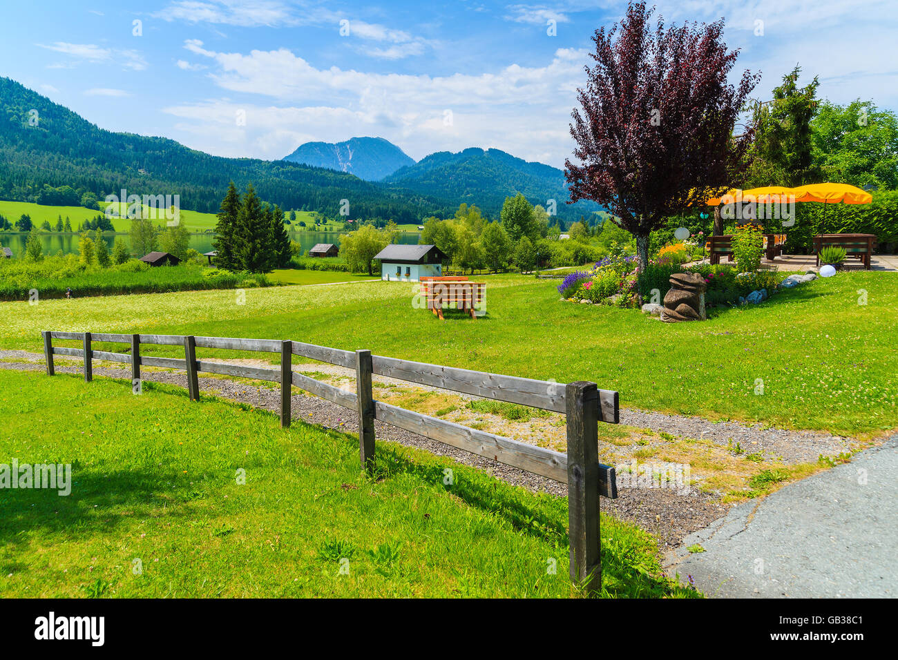 Countryside road with wooden fence on green meadow, Alps Mountains, Austria Stock Photo