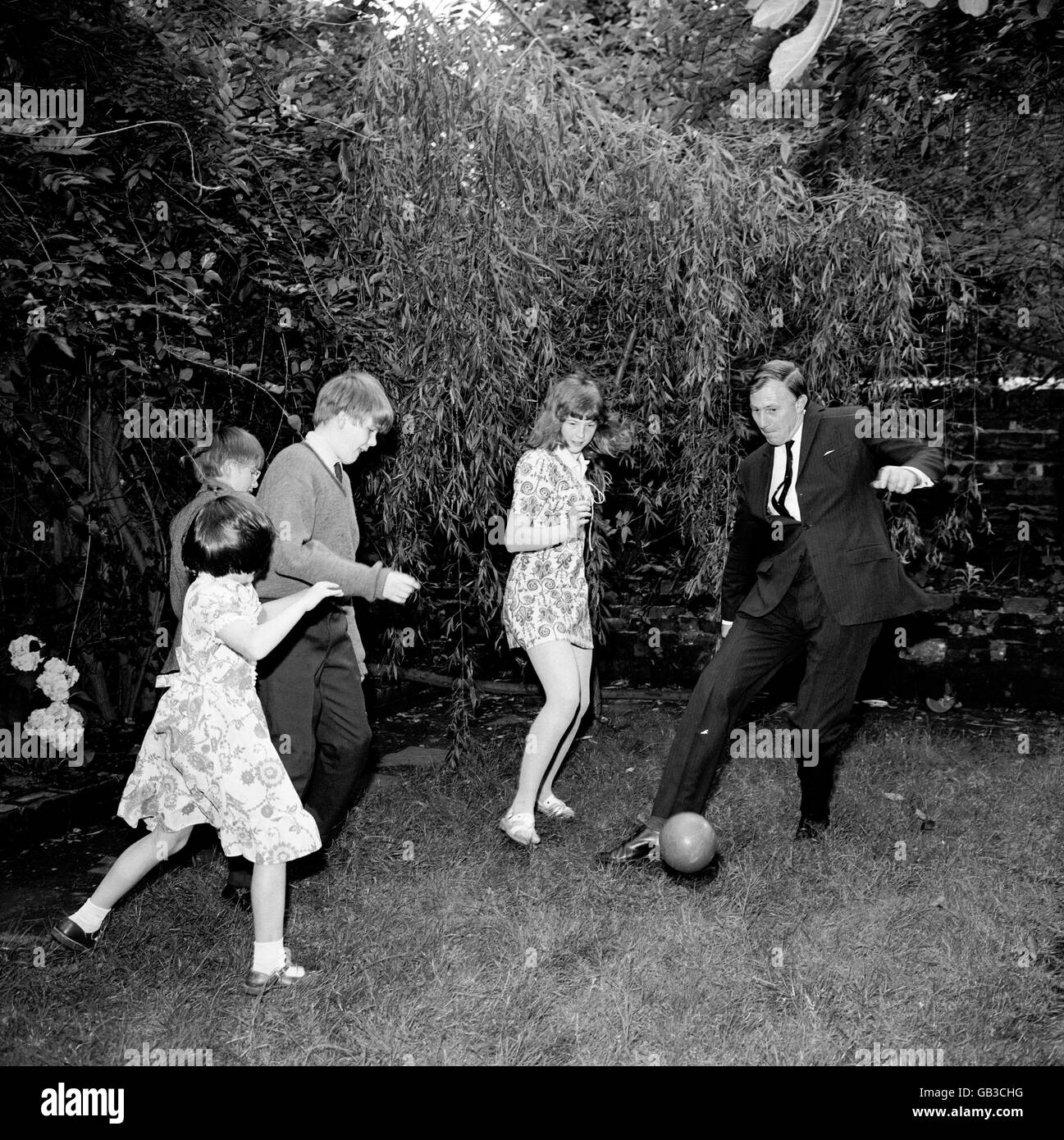 The Sports Council - Dr Roger Bannister. Dr Roger Bannister, Chairman of The Sports Council, playing football in the back garden with his four children Stock Photo