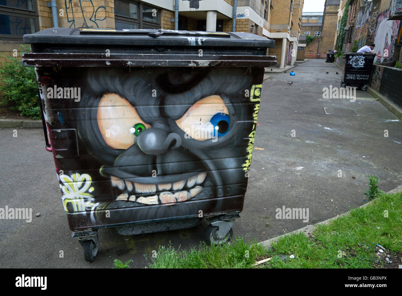 A menacing looking cartoon face painted on a bin in an alley near the Brick Lane area of Shoreditch, London, UK. Stock Photo