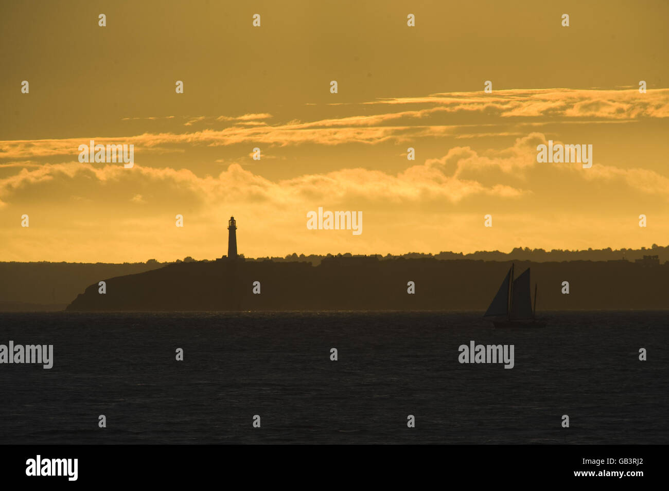 The sun casts a golden glow as it sets over Flatholme lighthouse situated in the Bristol Channel between Weston-super-Mare and Cardiff bringing some welcomed relief after the recent poor weather that has covered much of the UK. Stock Photo
