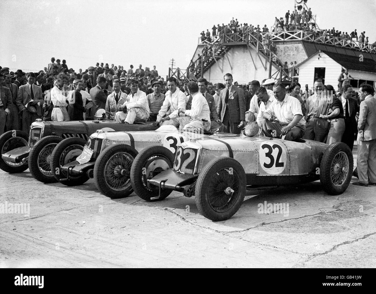 Motor Racing - British Empire Trophy - Brooklands. The top three drivers and their cars after the race, with winner Freddie Dixon (right, in car 32) celebrating with a glass of champagne. Stock Photo