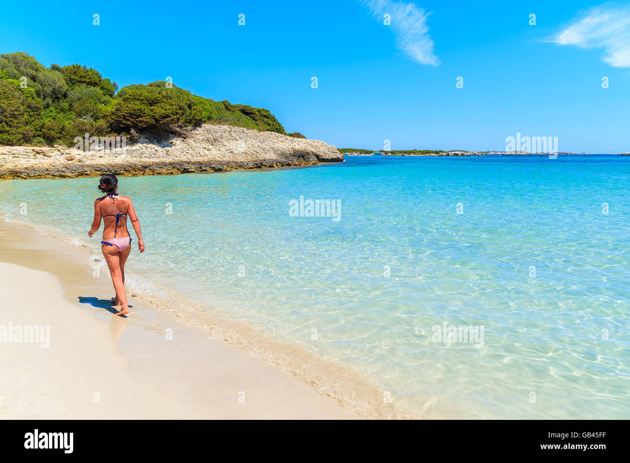 Unidentified attractive young woman in swimsuit walking along beautiful Petit Sperone beach on Corsica island, France Stock Photo
