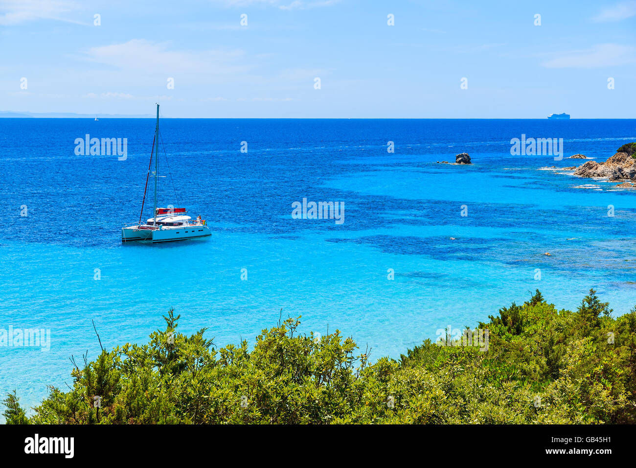 Catamaran boat in beautiful bay with turquoise sea water near Grande Sperone beach, Corsica island, France Stock Photo