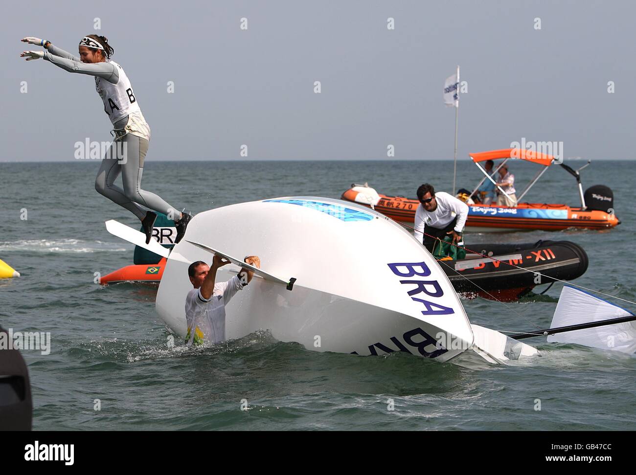 Brazil's Fernanda Oliveira and Isabel Swan bail into the water after their boat capsizes as they celebrate winning their final class race of the Women's 470 class during the 2008 Beijing Olympic Games' Sailing Centre in Qingdao, China. Stock Photo