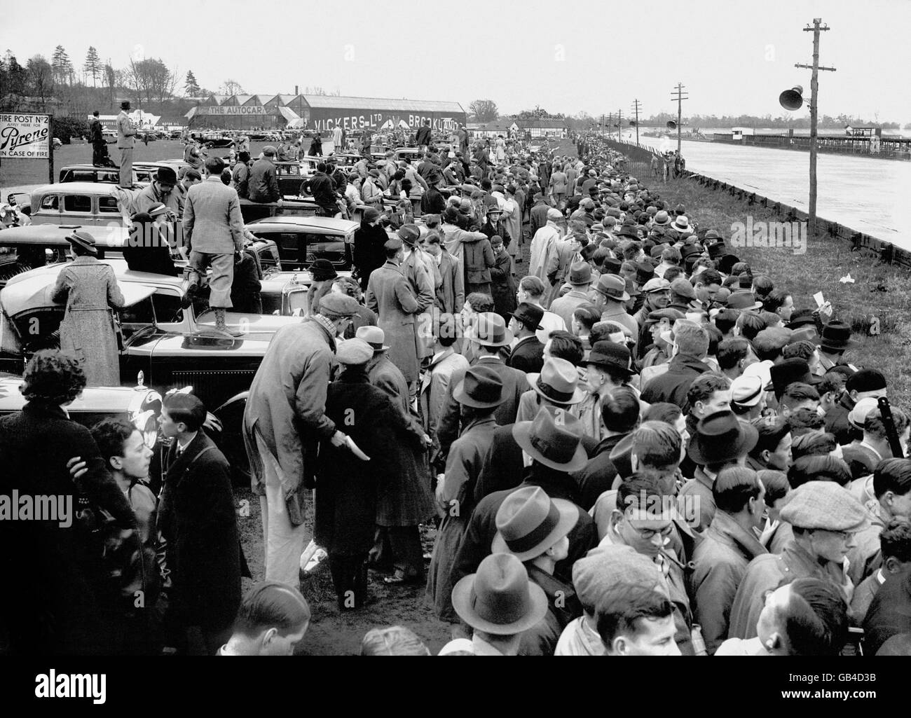 General view of the crowd, with some spectators standing on the bonnets of their cars to obtain a better view of the track at Brooklands. Stock Photo