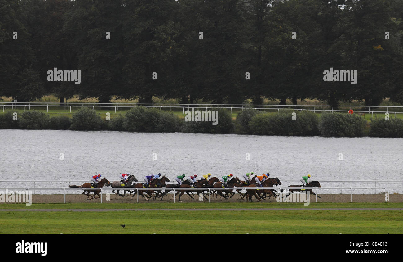 Premio Loco and George Baker (orange) sit on the rails down the back straight before winning the totescoop6 London Mile Heritage Handicap Stakes at Kempton Park Racecourse, Middlesex. Stock Photo