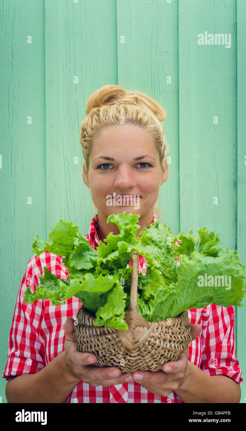 Blonde girl on a turquoise background holding basket with lettuce ...