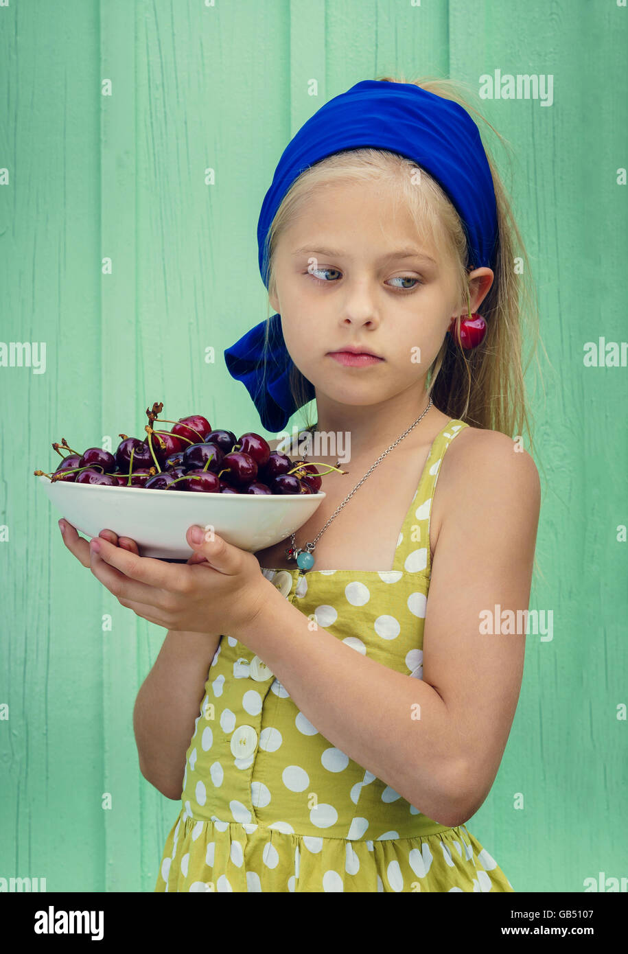 Beautiful blond girl on a background of turquoise wall holding a plate ...