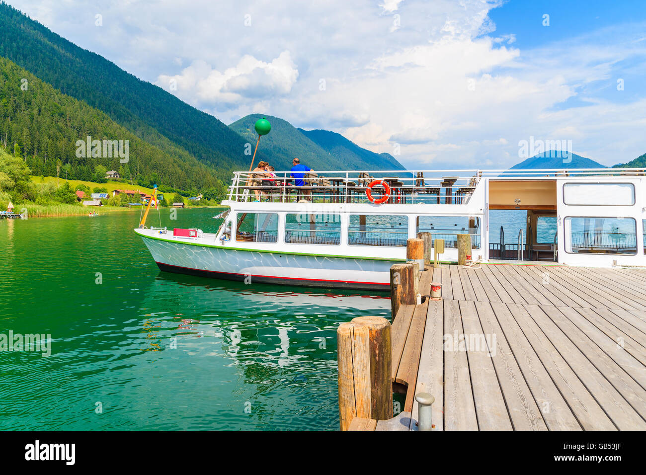 Tourist boat mooring to pier on shore of Weissensee lake in summer landscape of Alps Mountains, Austria Stock Photo