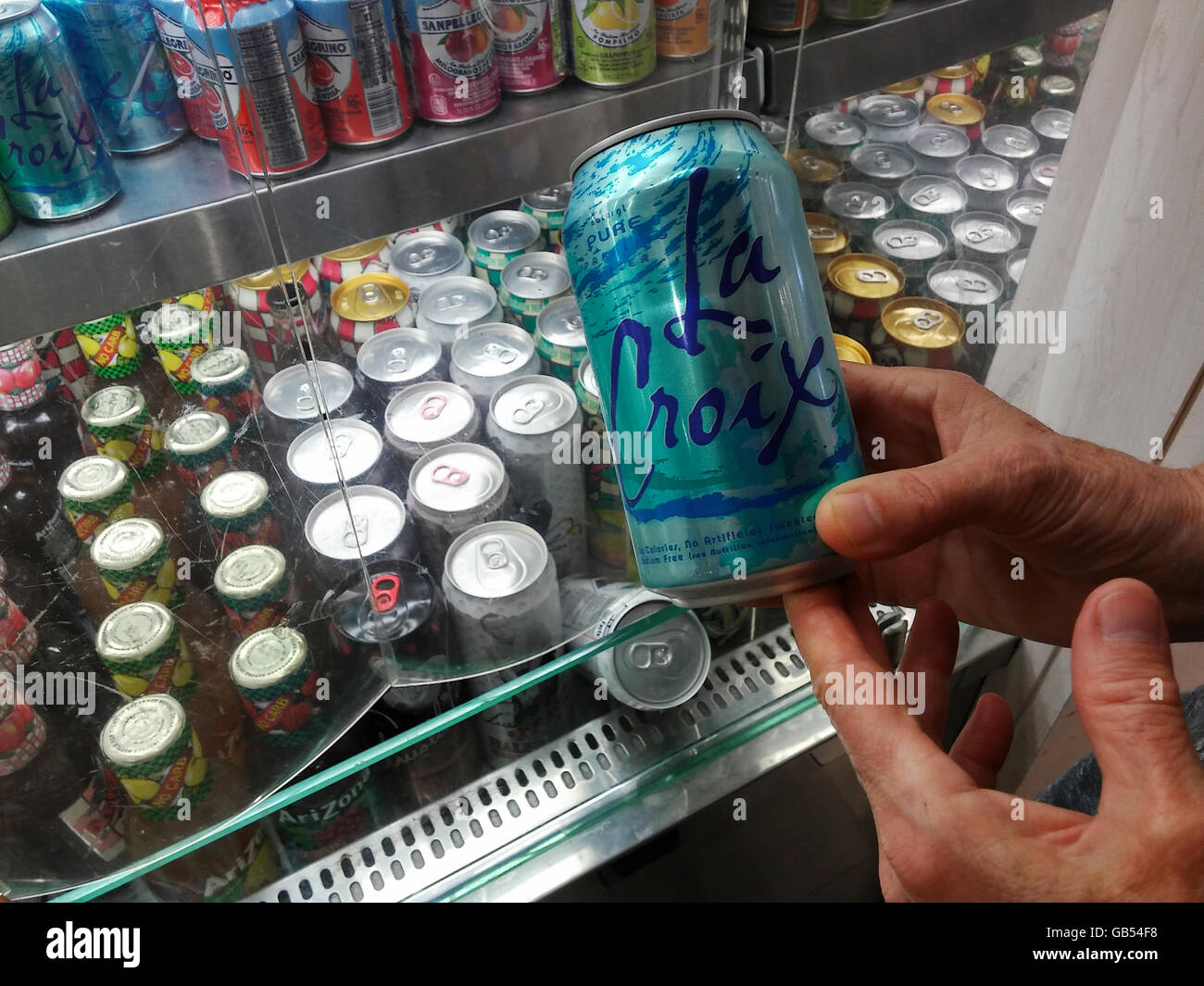 A shopper chooses a can of LaCroix sparkling water in a deli in New York on Monday, July 4, 2016. LaCroix eschews traditional advertising instead relying on their manipulation of social media to attract their millennial demographic. Sales have gone from $65 million in 2010 to $226 million in 2015 making it the number brand of flavored sparkling water in the U.S. (© Richard B. Levine) Stock Photo