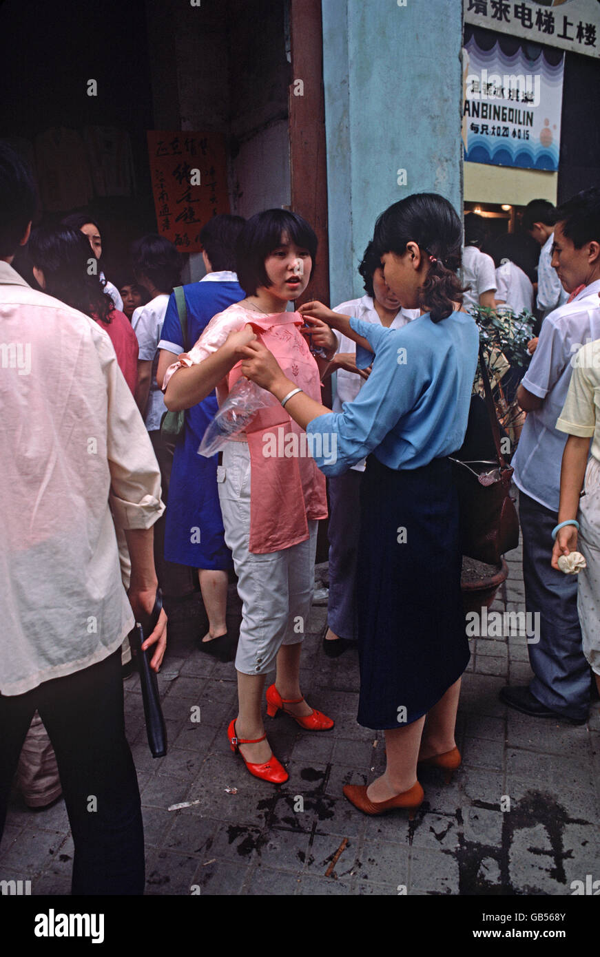 Chinese woman trying out clothes in Chengdu market, Sichuan Province, China Stock Photo