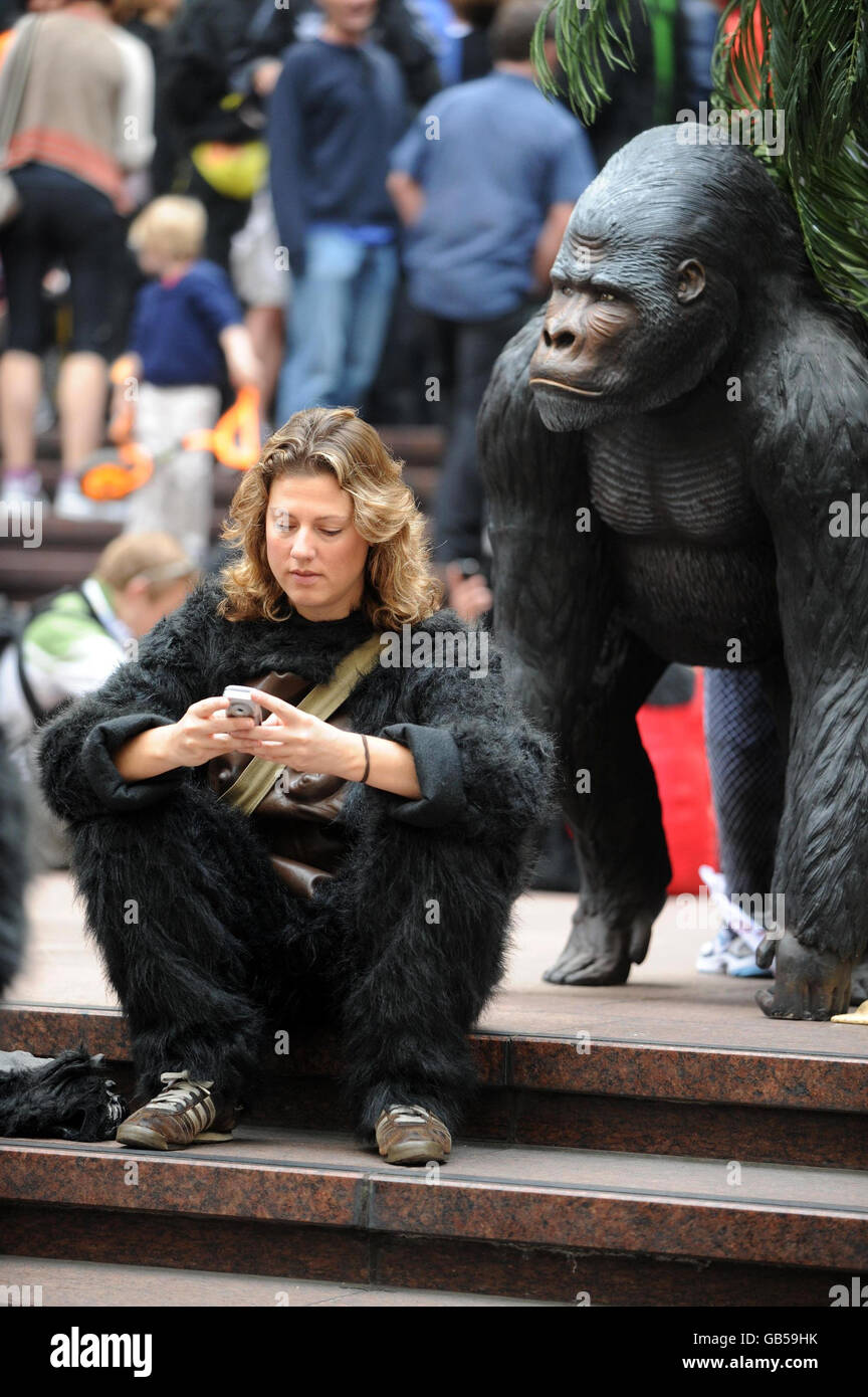 A woman uses her mobile phone with a model of a gorilla looking over her shoulder. Hundreds of