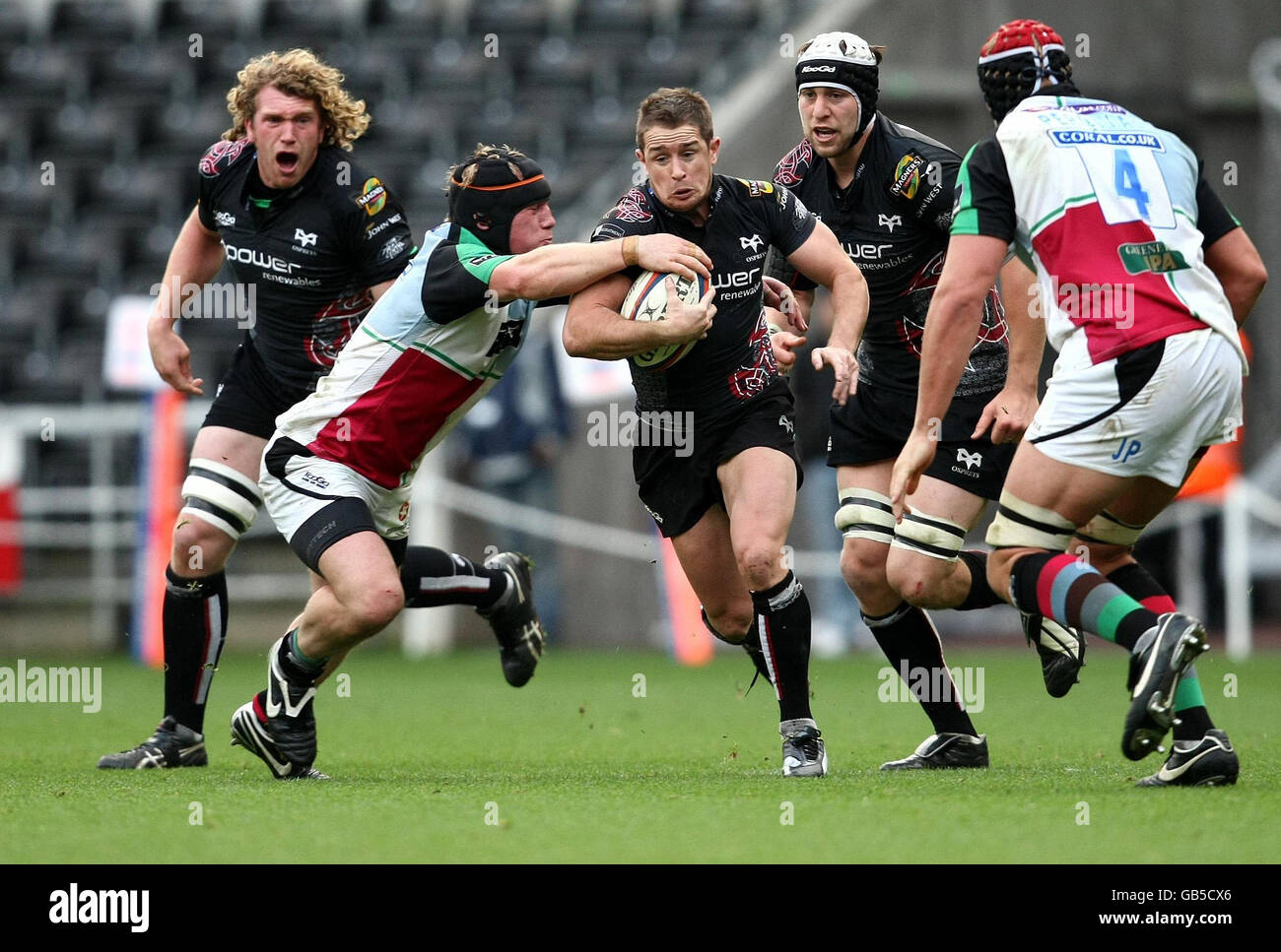 Osprey's Shane Williams stretches from the Harlequins defence of Mark Lambert and James Percival during the EDF Energy Cup at the Liberty Stadium, Swansea. Stock Photo