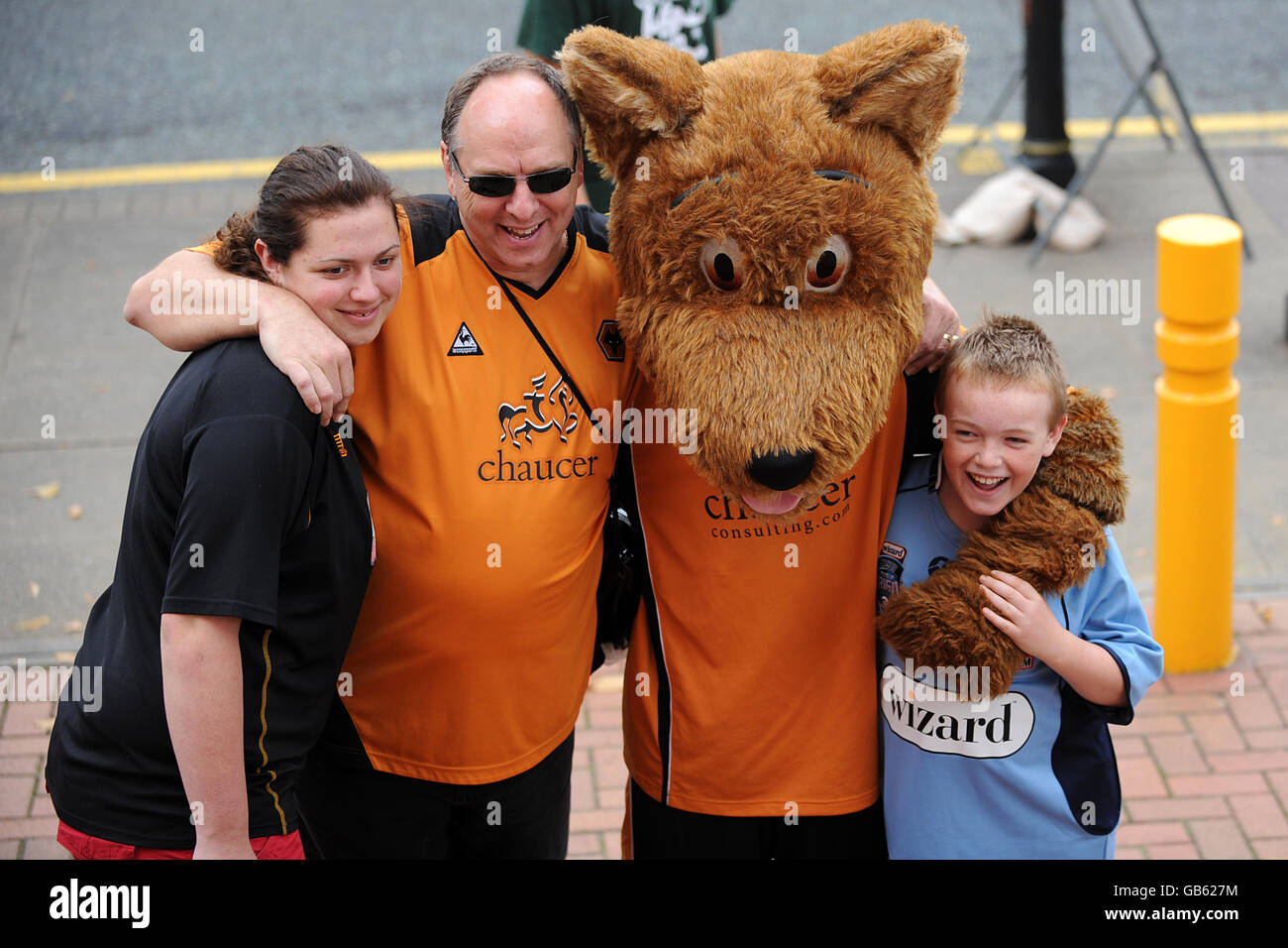 Fans pose for a photograph with Wolverhampton Wanderers' mascot Wolfie, outside the ground prior to kick off. Stock Photo