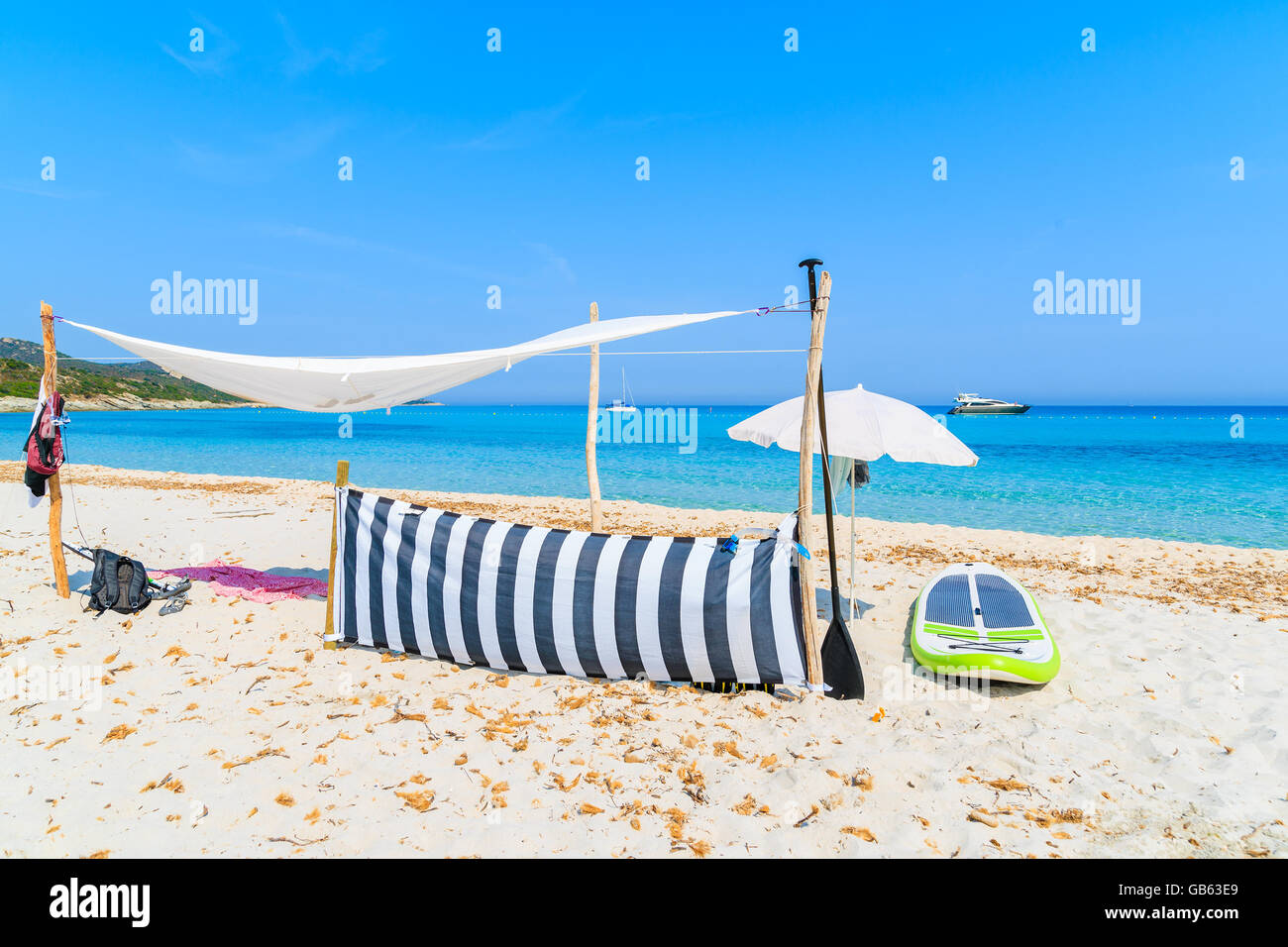 Sun shade and surfboard on white sand Saleccia beach, Corsica island, France Stock Photo