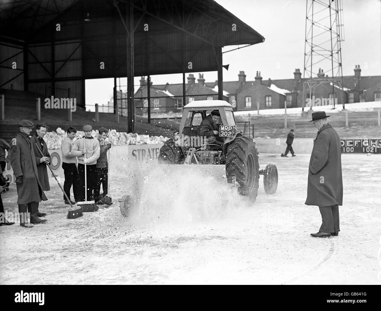 Leyton Orient manager Johnny Carey (r) looks on as a member of the Brisbane Road ground staff try to break the ice covering the pitch with a rotavator in a vain bid to get the pitch playable for the Third Round match against Hull City. Stock Photo