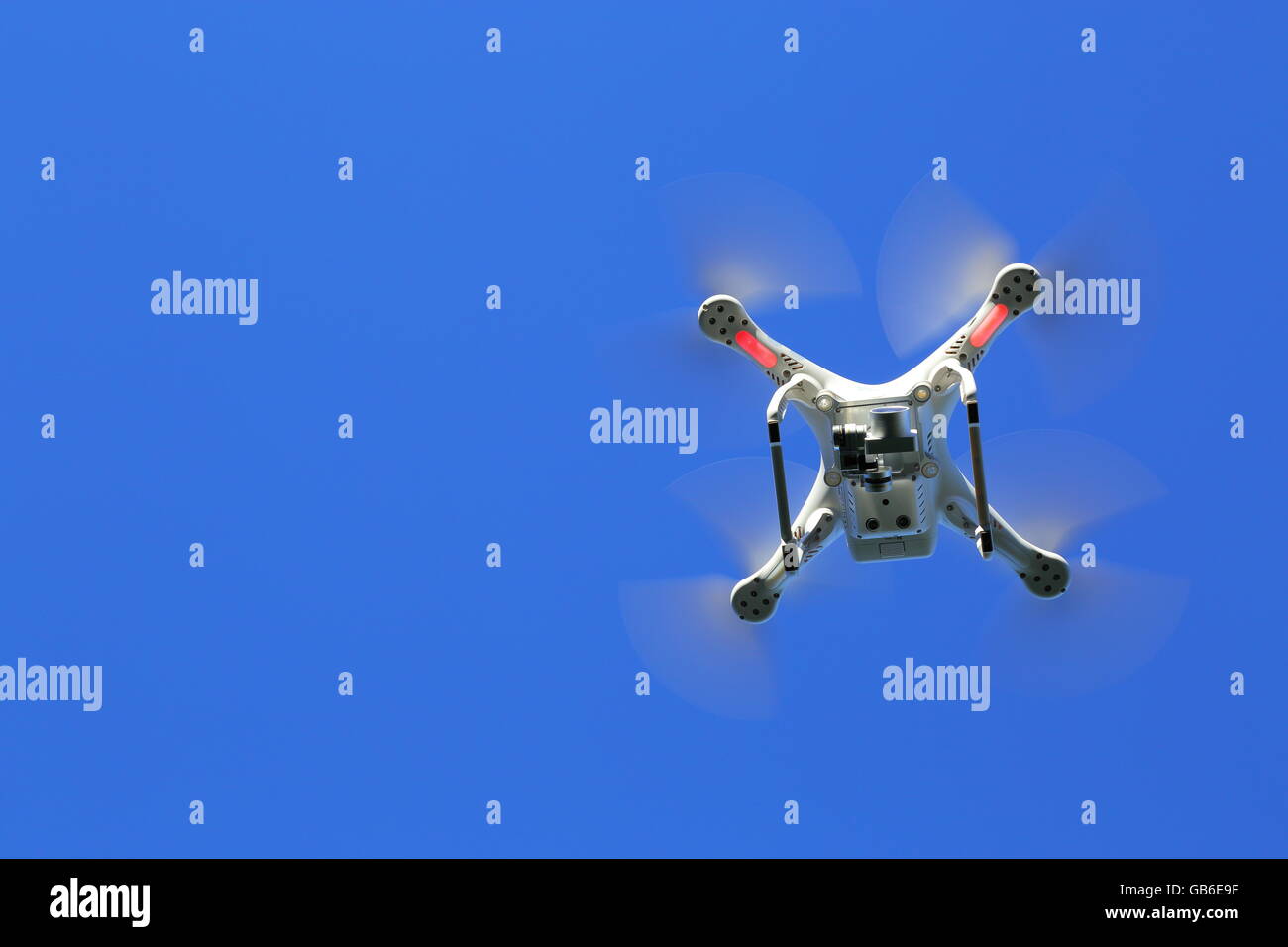 A drone, or UAV, or quadcopter, in flight under a vivid blue sky. Stock Photo