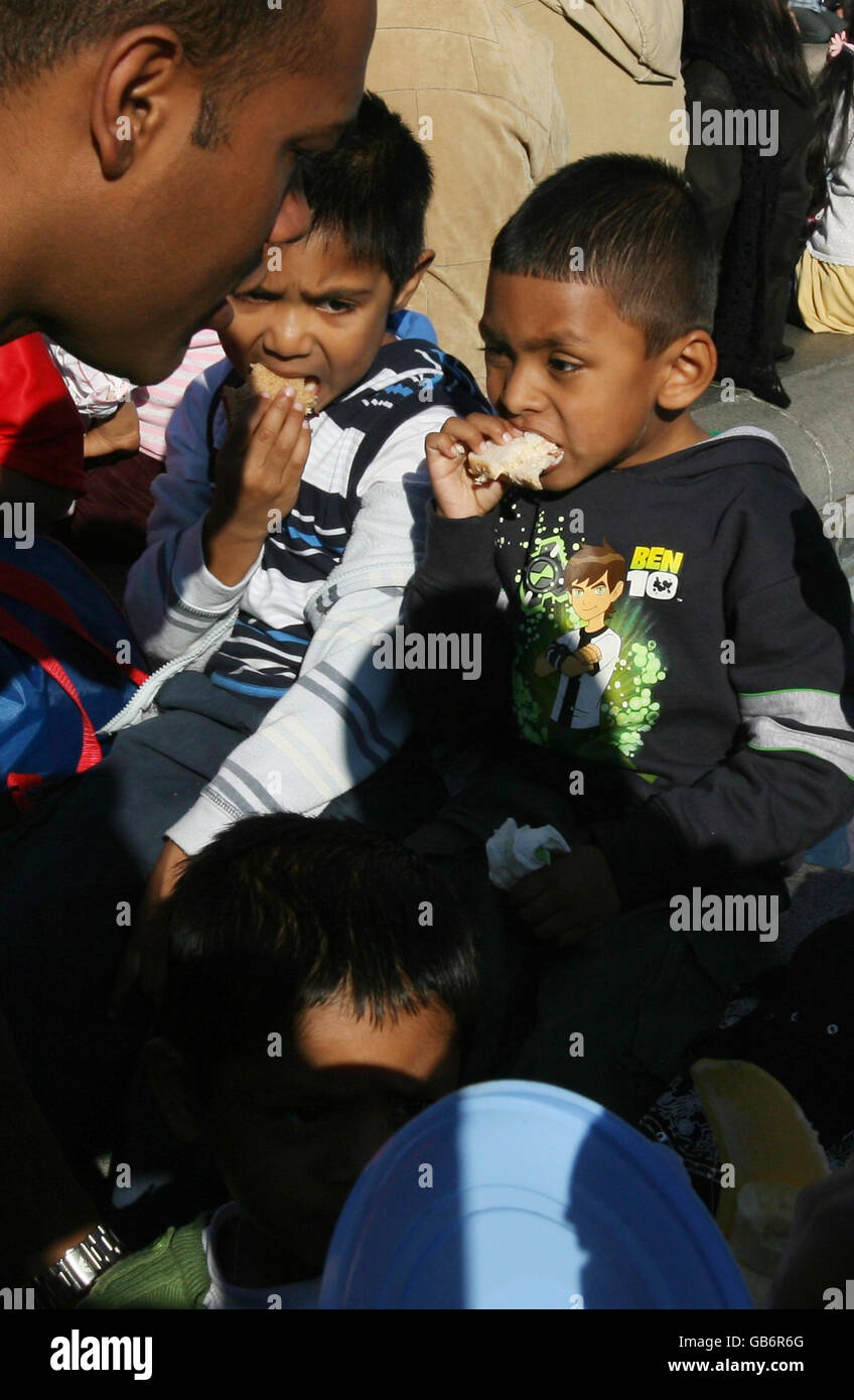 (left to right in background) Ahad Sheikh, 5, and his cousin Minhaj Uddin, 5, eat lunch as thousands gathered in Trafalgar Square in central London to celebrate Eid ul-Fitr which marks the end of Ramadan. Stock Photo