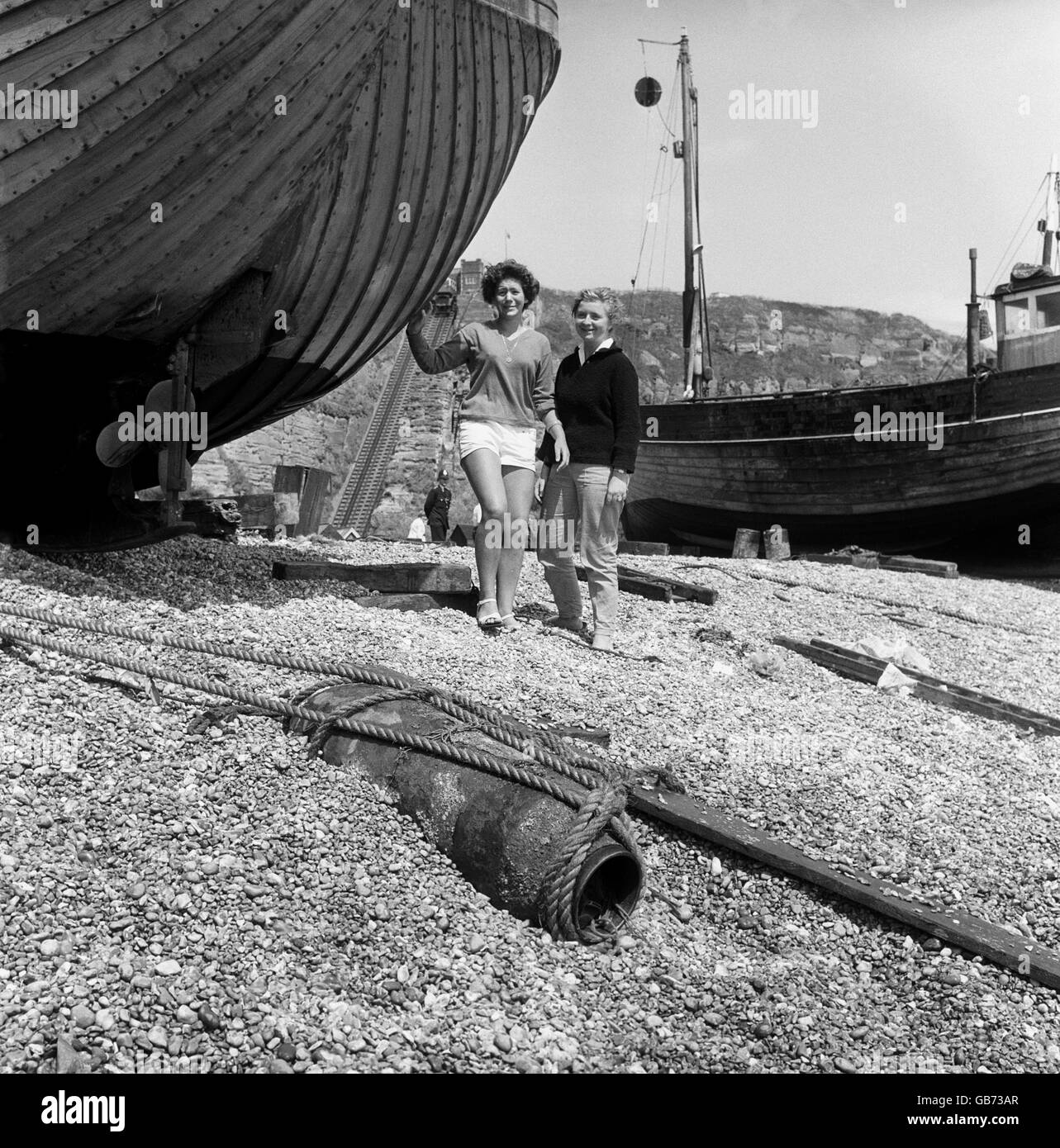 Helga Eckhout and Diana Woodall cautiously view the unexploded 500 pound German bomb on the beach at Hastings after it had been brought in by the fishing boat Little Paul, which caught the bomb in its trawl. Stock Photo