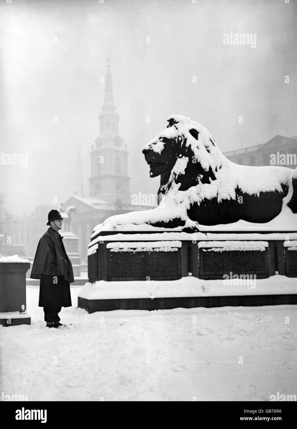 A policeman looks at one of the lions of Nelson's Column covered in a layer of snow, after a heavy snowfall in London. Stock Photo