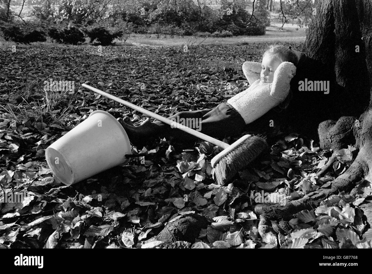 Three-year-old Erica Jane Shaw, taking a break after the exhausting autumnal task of sweeping up the leaves. Stock Photo