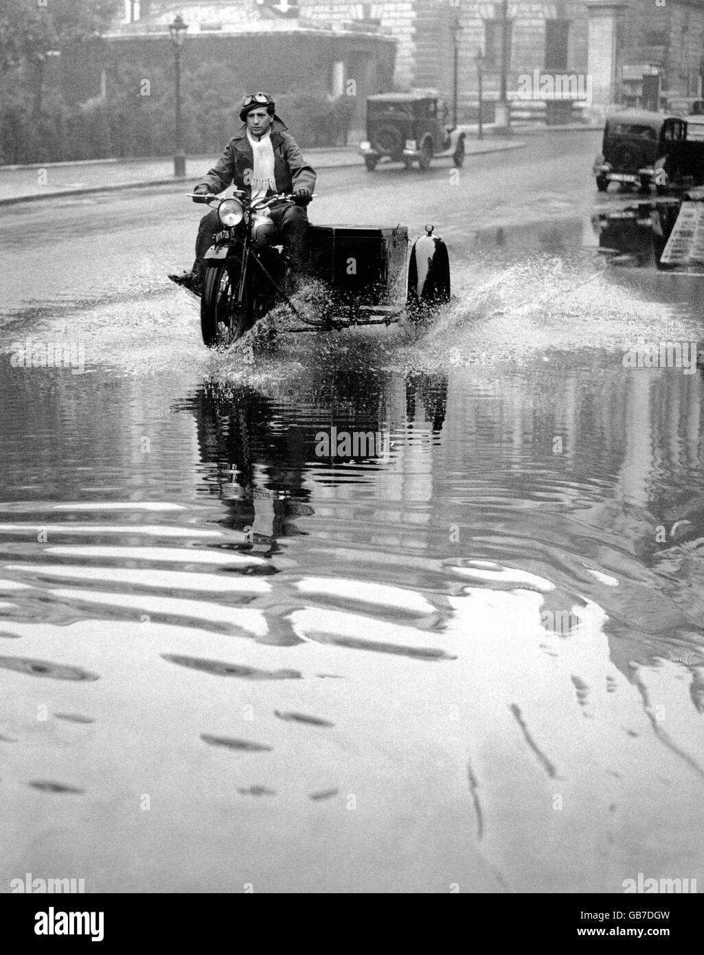 With his motorbike and side-car, an adventurous motorcyclist ploughs his way through the swamped roadway on Birdcage Walk, London, where the huge deluge of water caused flooding. Stock Photo