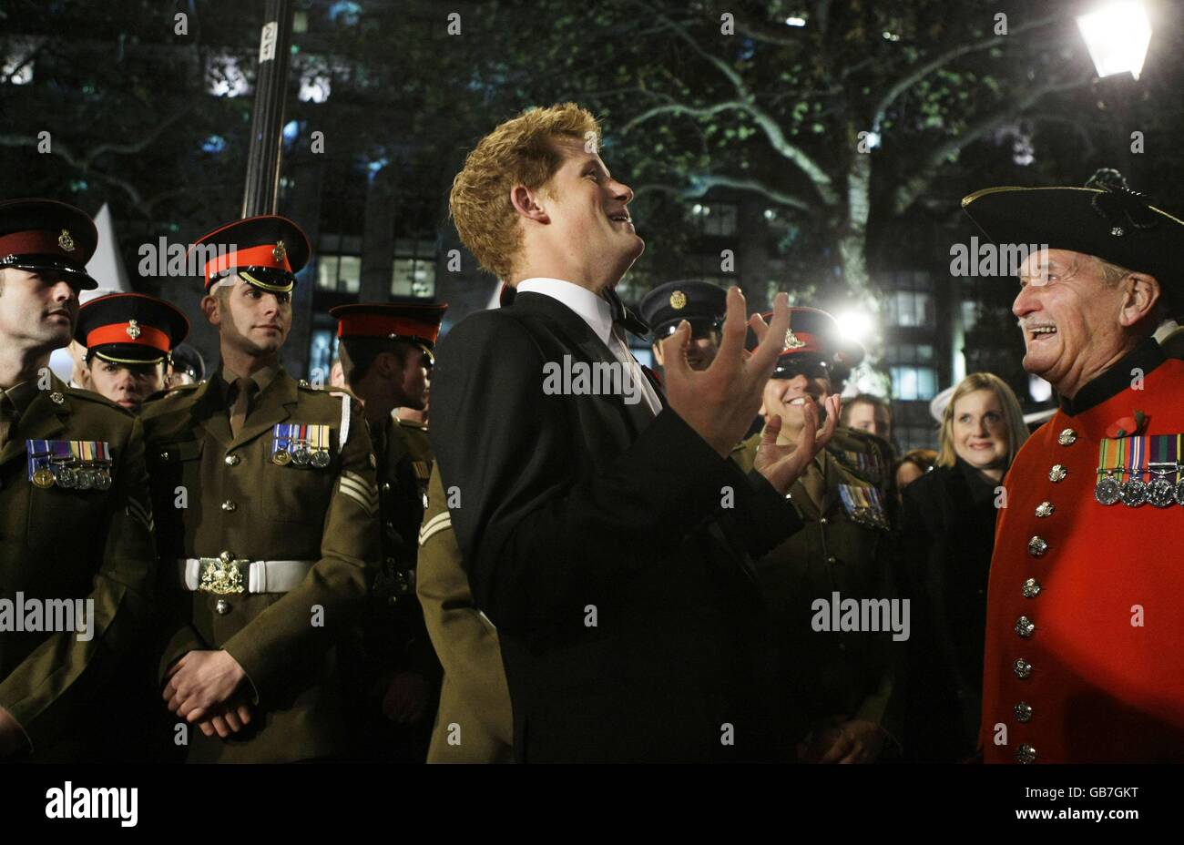 Britain's Prince Harry, center, jokes with Chelsea Pensioner Stan Pepper, right, as he meets military service personnel upon his arrival for the world premiere of the James Bond film 'Quantum of Solace' at a cinema in London. Stock Photo