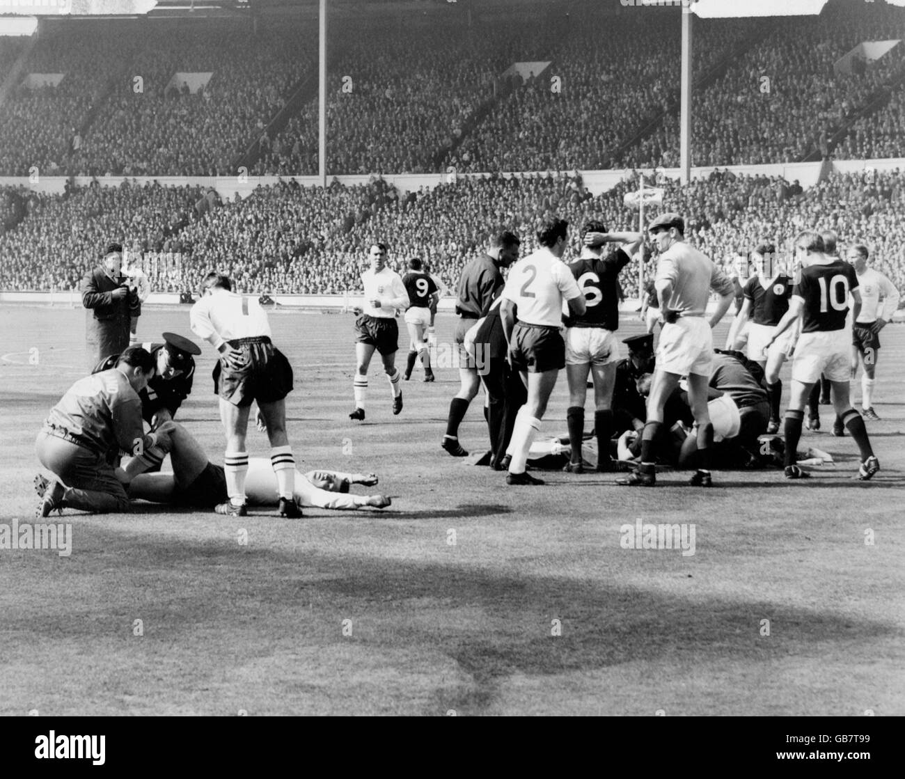 England's Bobby Smith (l, on floor) and Scotland's Eric Caldow (r, on floor) receive attention after colliding. Attending to Smith are England trainer Harold Shepherdson (l) and England's Bryan Douglas (7), while among those gathered around Caldow are (l-r) England's Bobby Charlton, Scotland's Denis Law, John White, Dave Mackay, Bill Brown and Jim Baxter, and England's Jimmy Armfield (2). England's Jimmy Greaves (c) is trotting over to check on his mate Smith Stock Photo