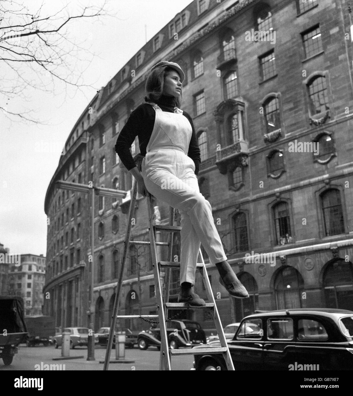 Up a ladder wearing the latest in bib and brace overalls is Suzanne Kennedy in The Aldwych, London. The new overalls are by Lybro of Liverpool. Stock Photo