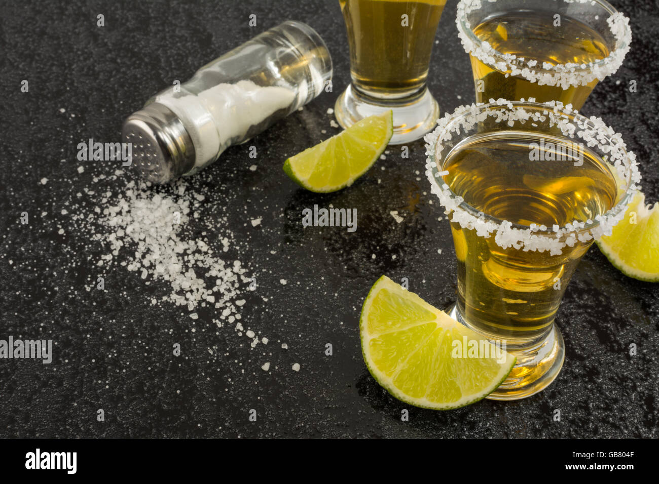 Gold tequila shot with lime on black background, close up. Tequila shot