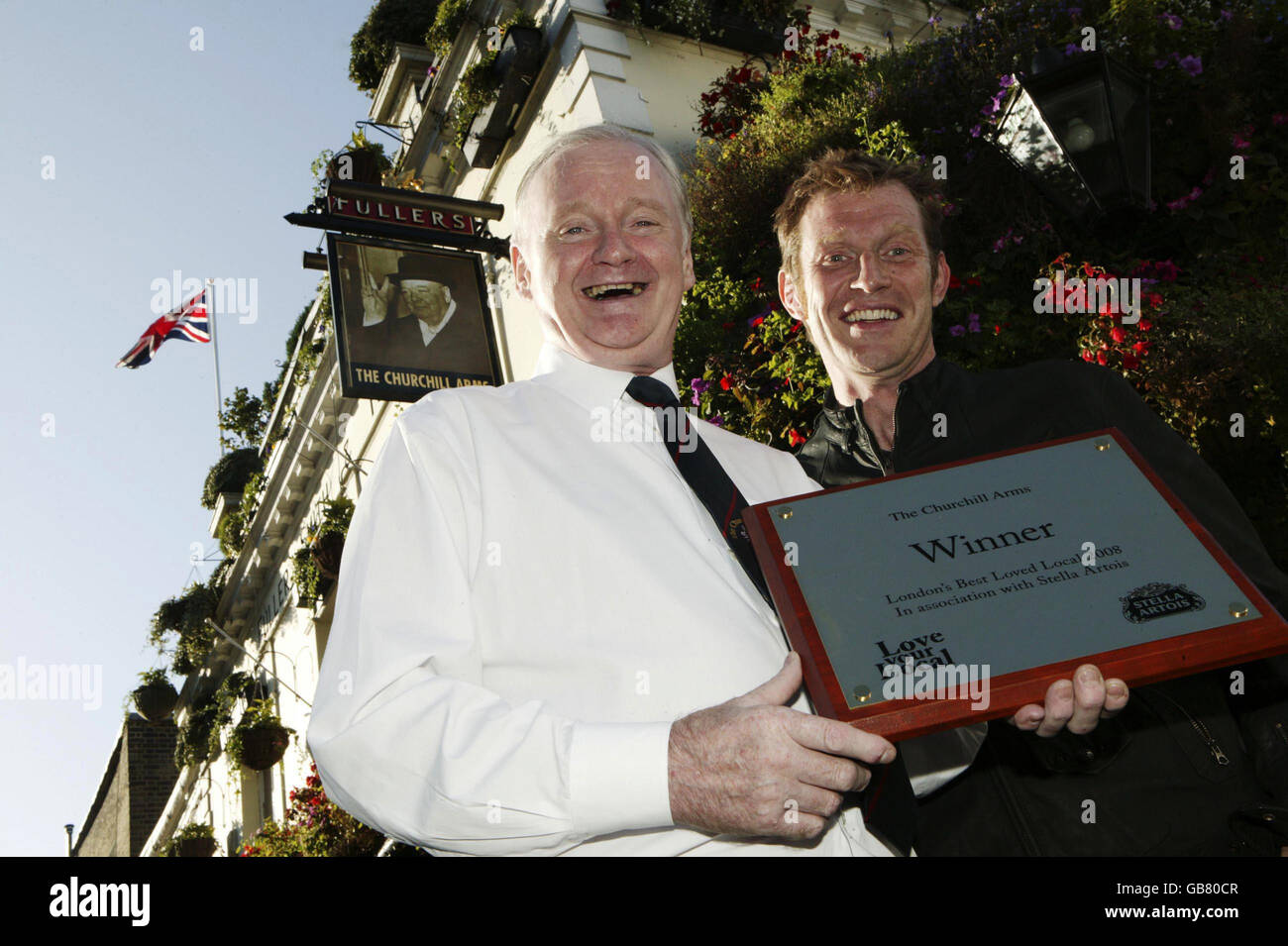 Landlord Gerry O'Brien, winner of the Stella Artois Love Your Local campaign and actor Jason Flemyng hold the winner's plaque outside The Churchill Arms on Kensington Church Street, London. Stock Photo
