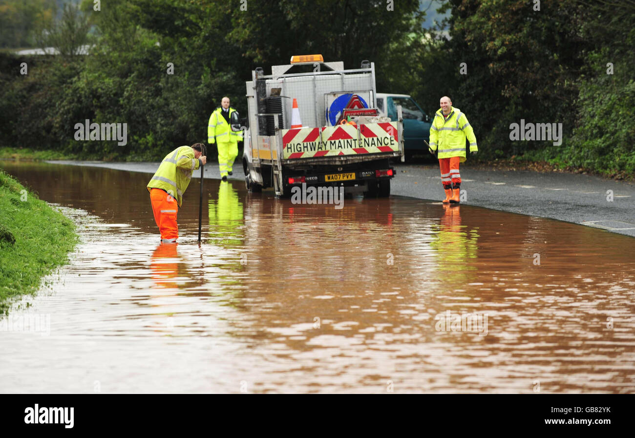 Highway maintenance workers work to clear drainage on the B3181 in Westcott, Devon after heavy overnight rain closed the road and caused travel problems in the region. Stock Photo
