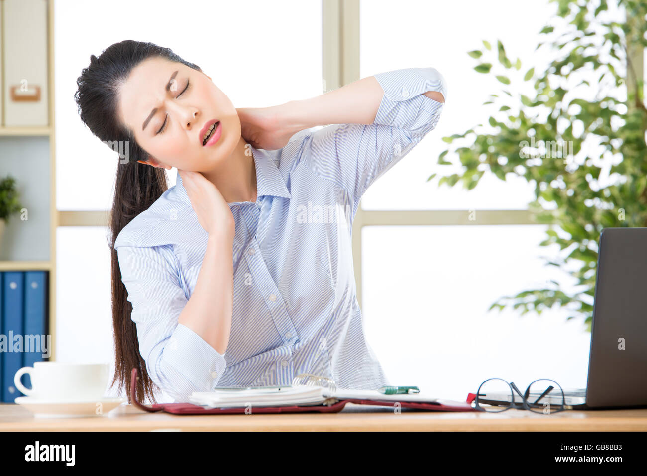 Young asian business woman with pain in neck in office Stock Photo