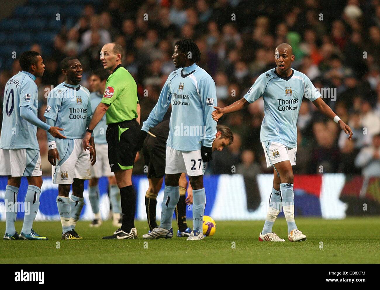 Manchester City players complain to referee Mike Dean as Gelson Fernandes leaves the field dejected after he is shown the red card Stock Photo