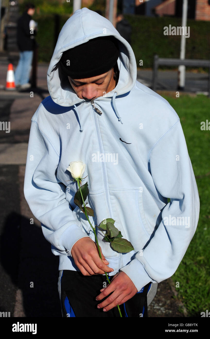 A mourner brings a flower to the scene of a shooting in Caxton Street in Derby after Kadeem Blackwood, a 15-year-old boy was shot dead. Stock Photo
