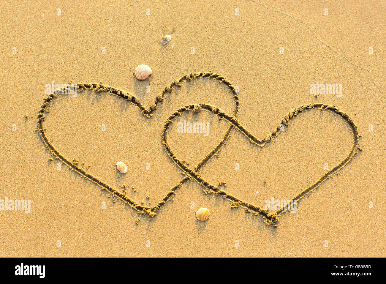 Two of hearts drawn on a sandy sea beach. Stock Photo