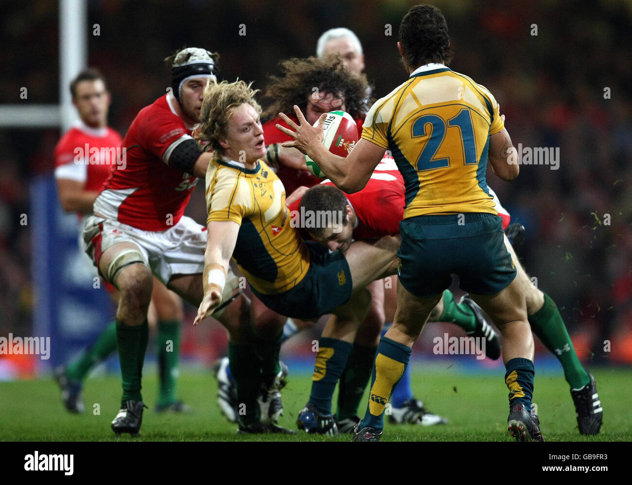 Australia's Ryan Cross offloads the ball under pressure from Wales' Andrew Bishop during the Invesco Perpetual Series match at the Millennium Stadium, Cardiff. Stock Photo