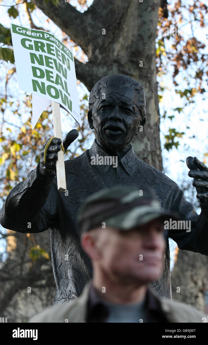 A Green Party placard is strapped around the right hand of the statue of Nelson Mandela in Parliament Square, Westminster, central London, as environmental campaigners marched there from Grosvenor Square 'to demand policies to match the Government's rhetoric on climate change'. Stock Photo