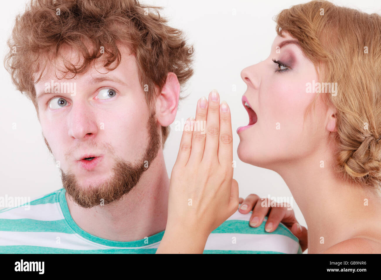Closeup woman telling an astonished surprised man some secrets, couple ...