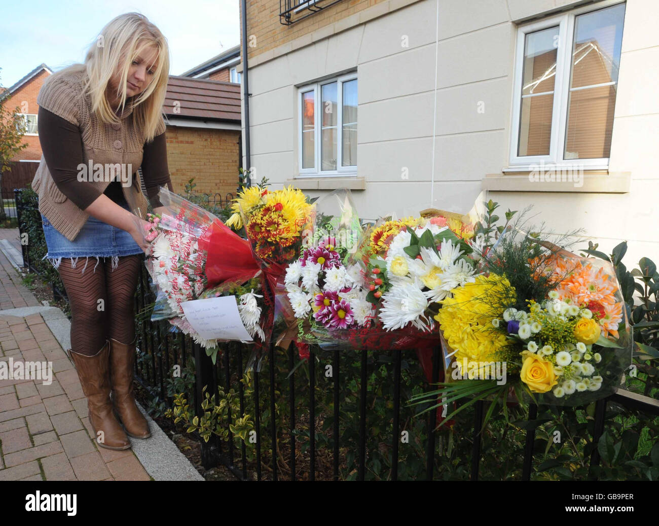 Flowers left at the scene in Horfield, Bristol, where a pensioner died after a car thief ran him over with his own Skoda, are inspected by Gemma who tried to help at the incident. Stock Photo
