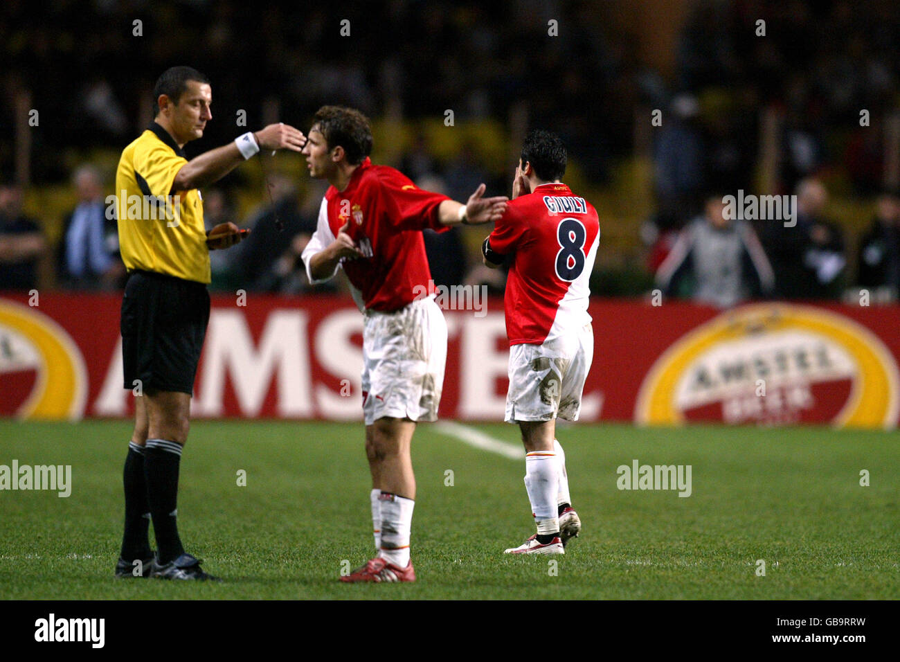 Monaco's Captain Ludovic Giuly (r) heads for the exit after receiving a red card from referee Zeljko Siric (l) as teammate Lucas Bernardi argues his case Stock Photo
