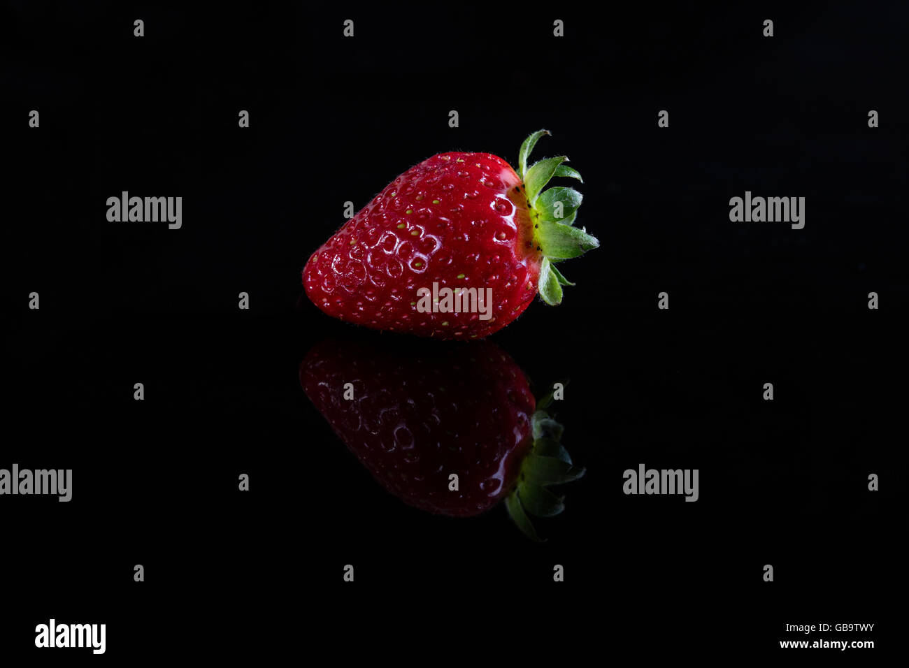 One juicy strawberry on black background Stock Photo - Alamy