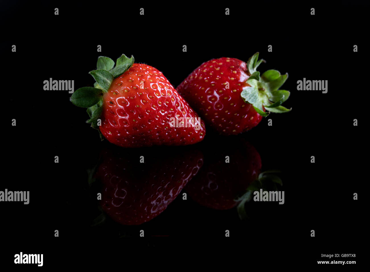 Two juicy strawberry on black background Stock Photo - Alamy