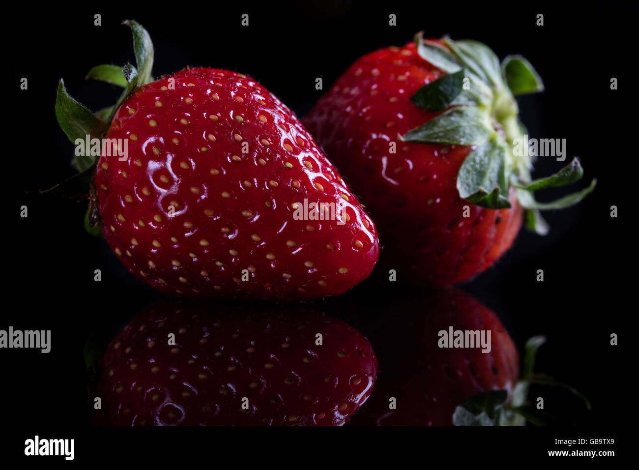 Two juicy strawberry on black background Stock Photo - Alamy