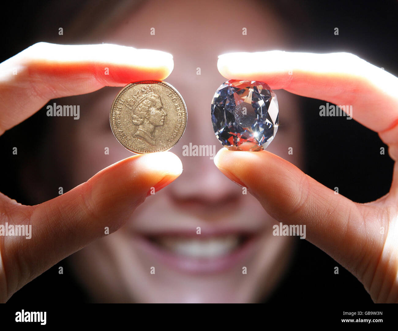 Christie's employee Becky Markley, holds up the Wittelsbach Diamond (right), estimated at 9 million, besides a ten pence piece, during a viewing at Christie's in Mayfair, central London. Stock Photo