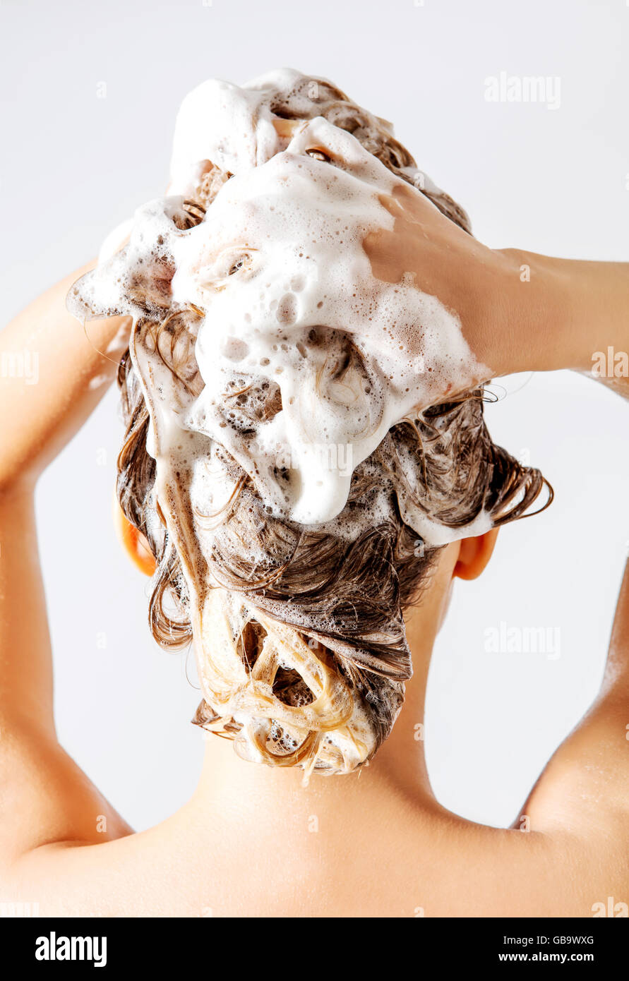 Woman taking a shower and shampooing her hair. Isolated on white. Stock Photo