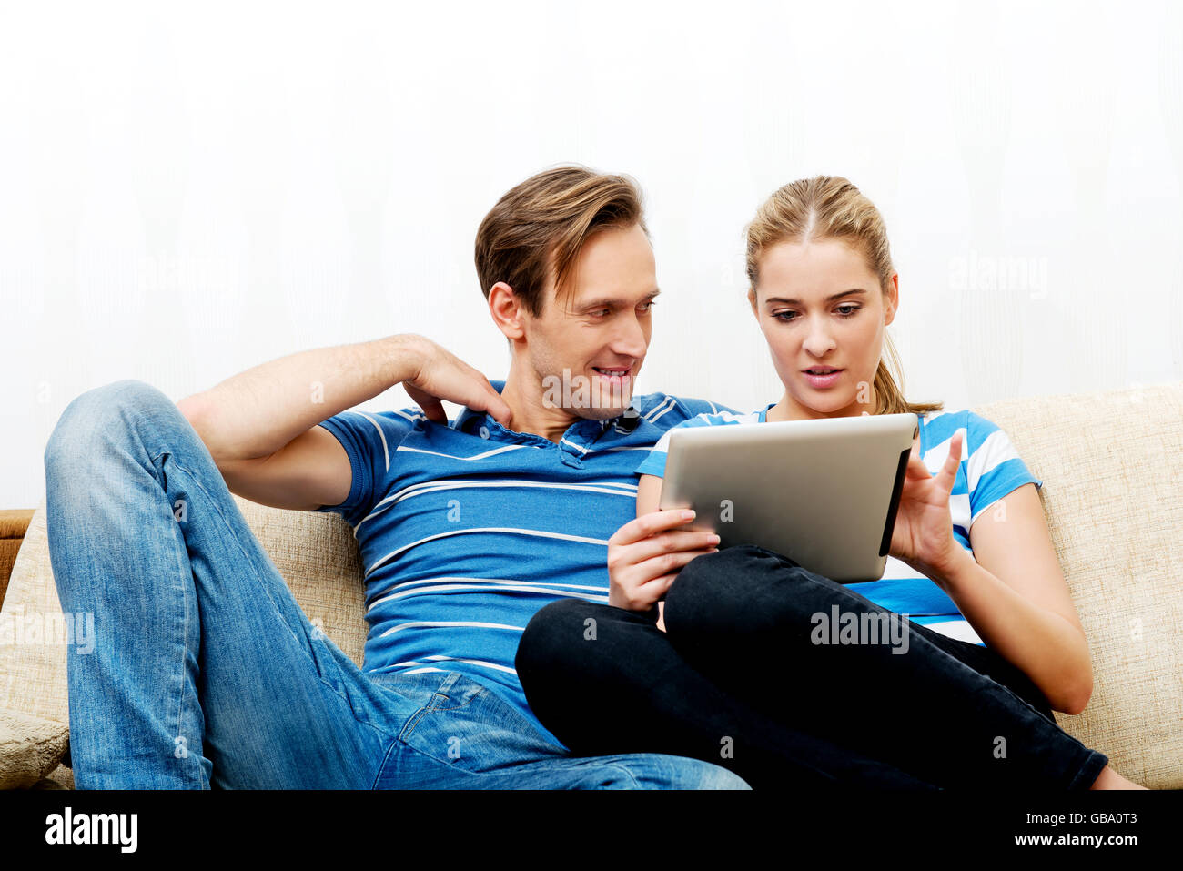 Young couple sitting at home and looking for something on tablet Stock Photo