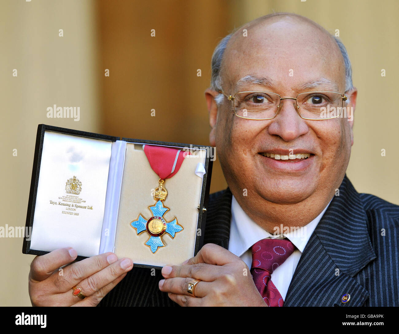 Indian-born businessman and philanthropist Raj Loomba holds his CBE for charitable services to poor widows and their children overseas and for his work in promoting the interests of the UK and India, outside Buckingham Palace after it was presented to him by the Prince of Wales. Stock Photo